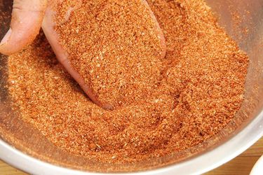 A hand lifting some dry bbq rub out of a metal mixing bowl.