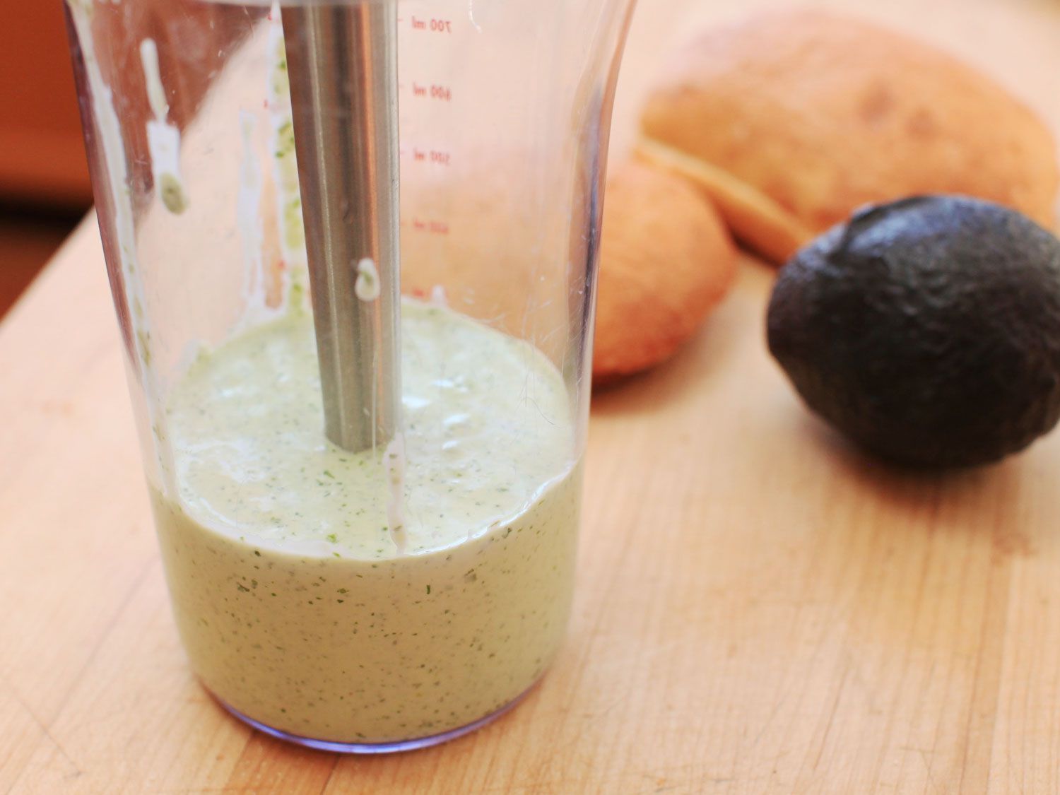 An immersion blender in a jar containing green sauce for Peruvian grilled chicken. 