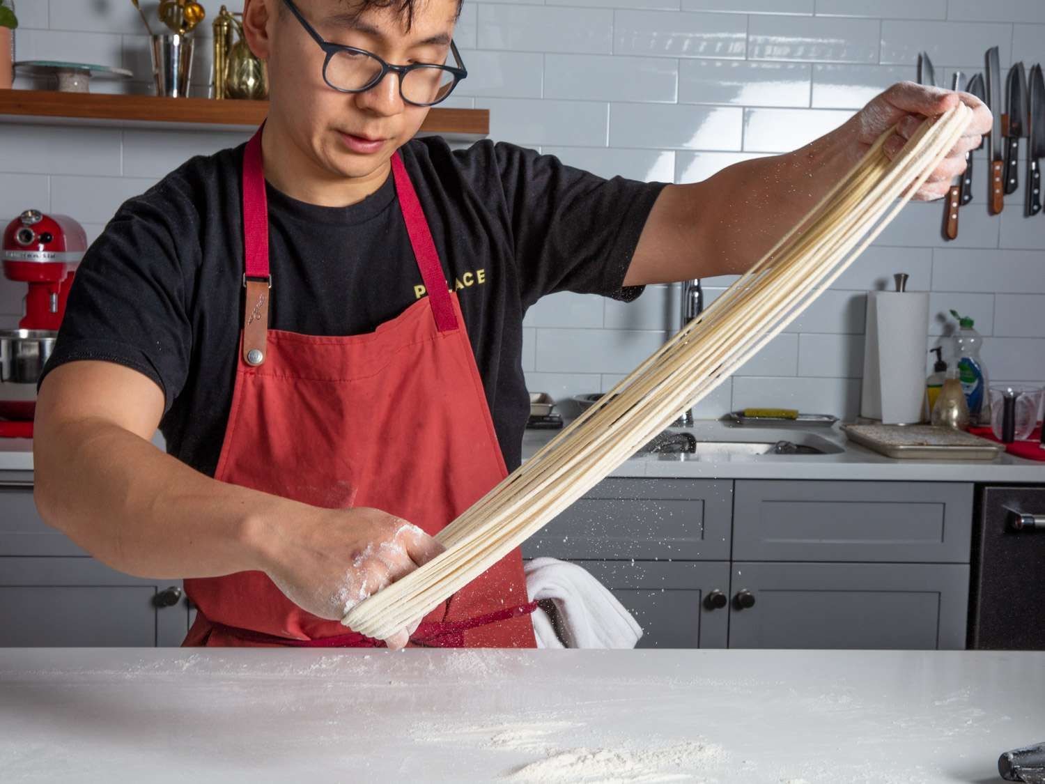 Streching dough between two hands to make hand-pulled noodles.