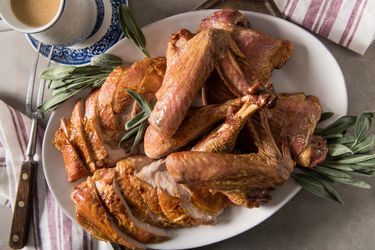 A whole roasted turkey broken down into its parts and nicely reassembled on a platter and garnished with fresh sage