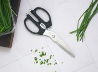 shun kitchen shears on a white tile surface with snipped chives