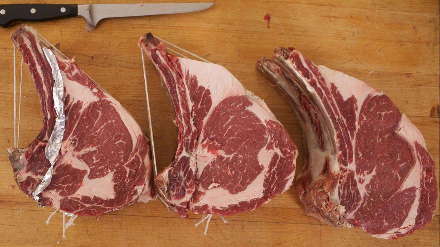 Bone-in steaks on a wooden surface