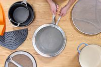 a person placing the all-clad splatter screen on a skillet