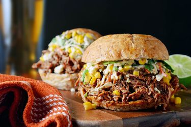 Profile view of a chorizo-spiced pulled pork sandwich with Mexican street corn slaw.