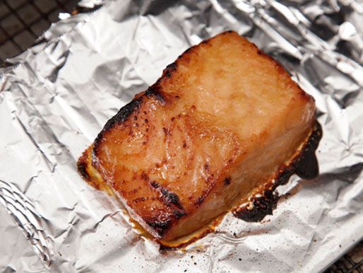 A piece of cooked miso-glazed salmon fillet that looks charred and golden. 