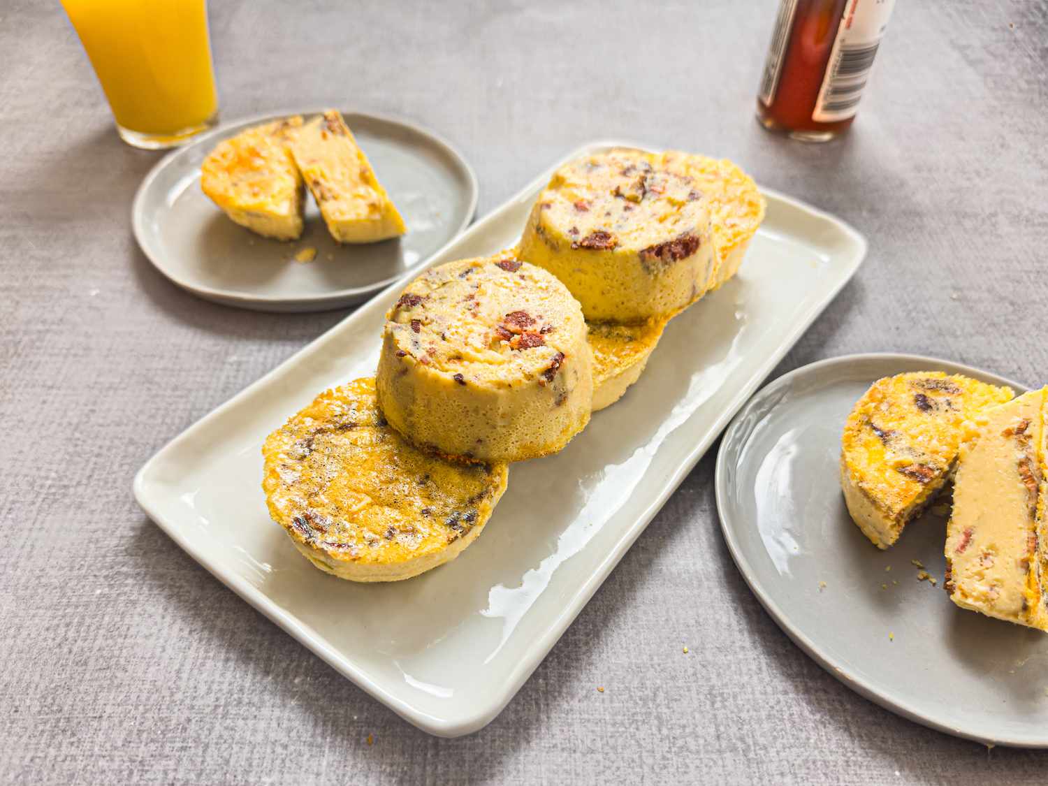 Plated muffin tin bacon egg bites arranged on a rectangular plate with additional servings on smaller plates