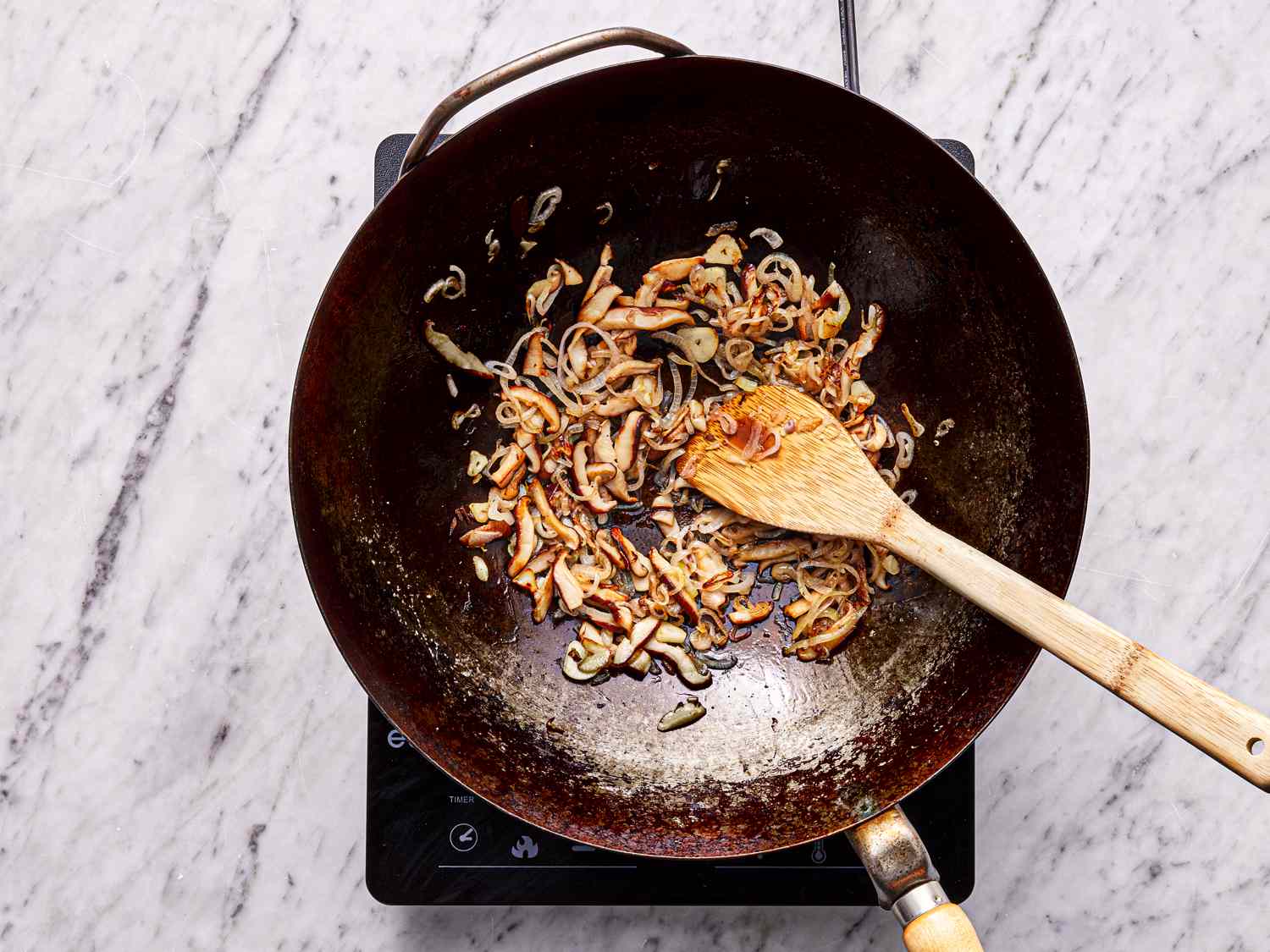 Overhead view of mushrooms and onions cooking in a wok