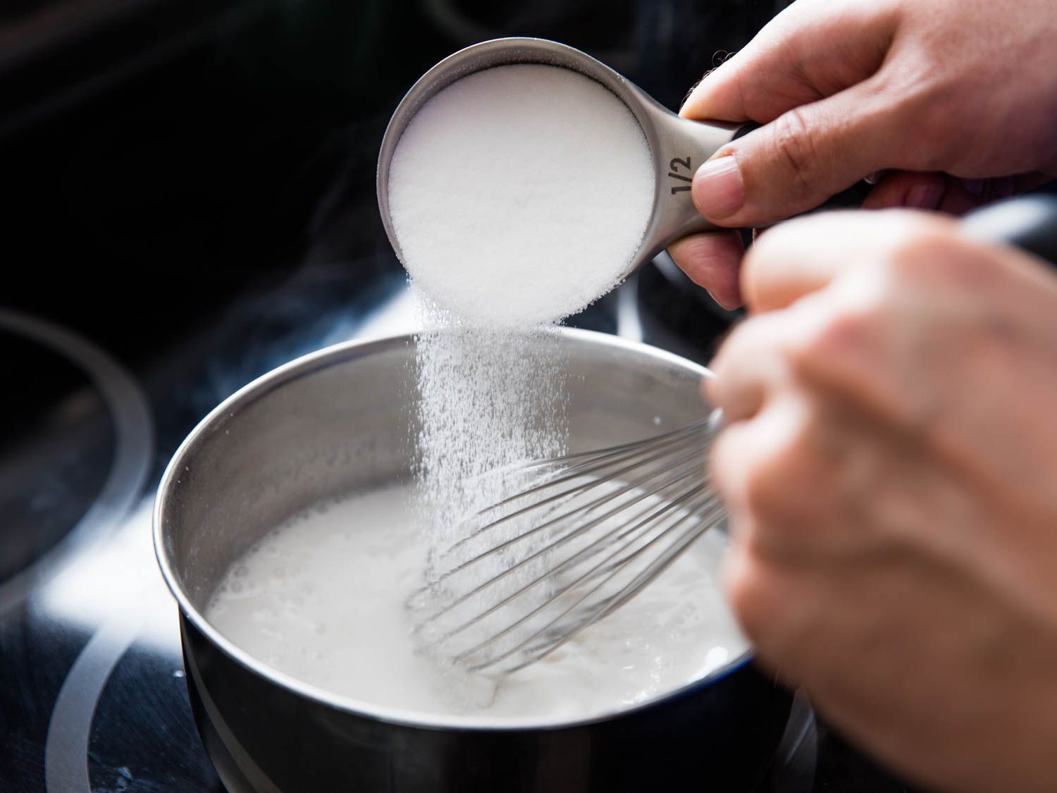 Sugar being whisked in to a pot of warming coconut milk.