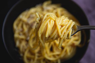 Spaghetti carbonara getting twirled on a spoon.