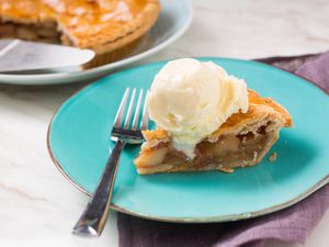 A slice of apple pie topped with a scoop of cheddar ice cream.