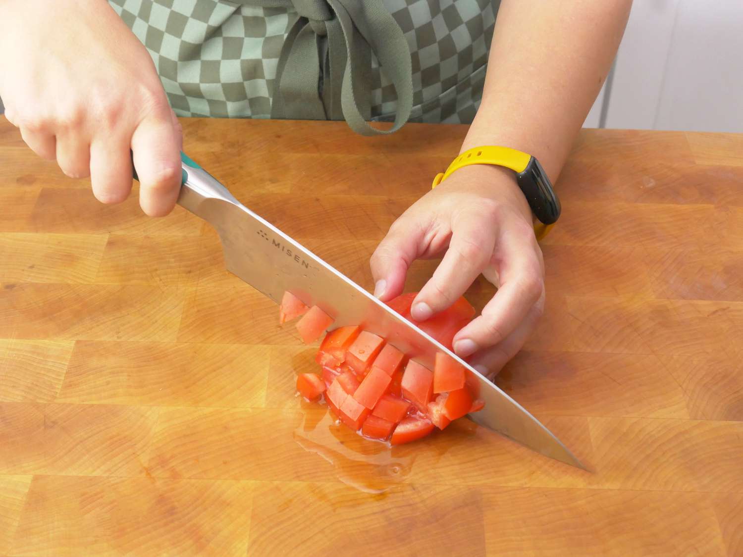 a person dicing a tomato with the misen chef knife