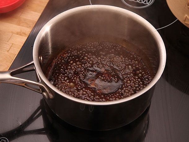 A pork belly marinade reducing in a small pot into a syrupy sauce