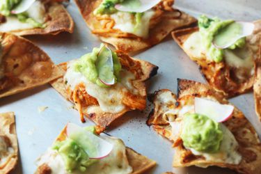 Individually-topped chicken tinga nachos with cheese, guacamole and sliced radish.