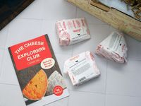 three wrapped wedges of cheese and a pamphlet