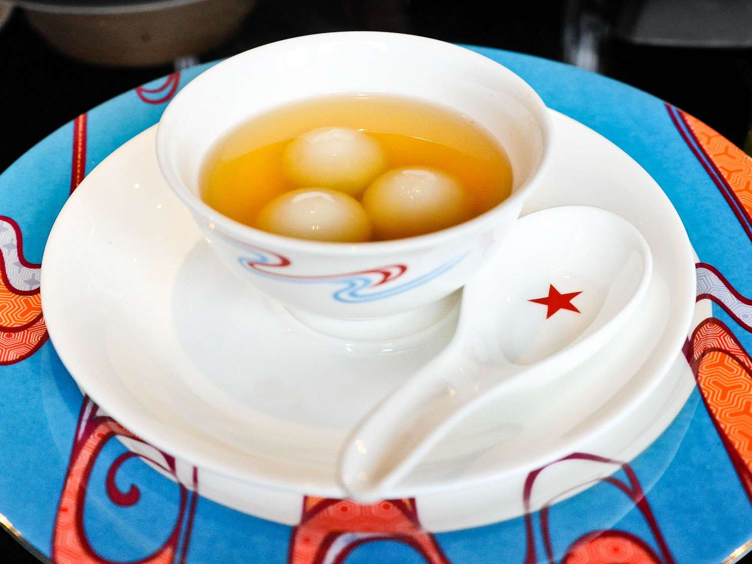 Tang Yuan (Glutinous-Rice Balls in Sweet Syrup) served in a small bowl with a soup spoon.