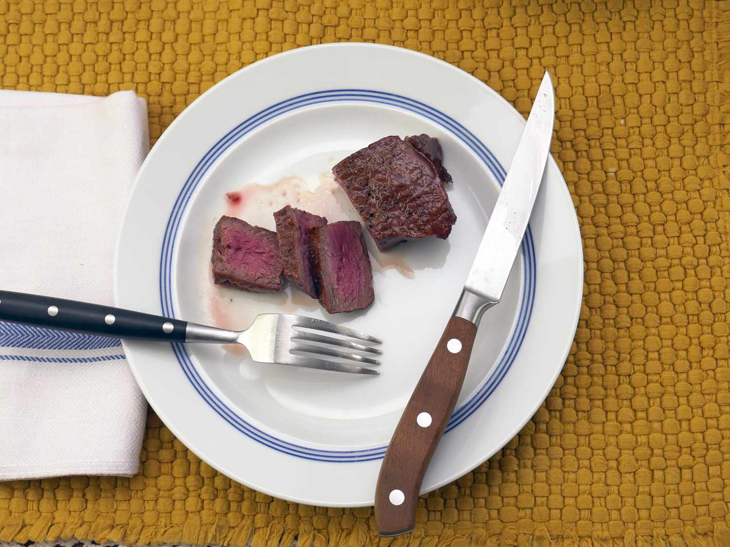 a cut up piece of steak on a plate with the victorinox knife to the side