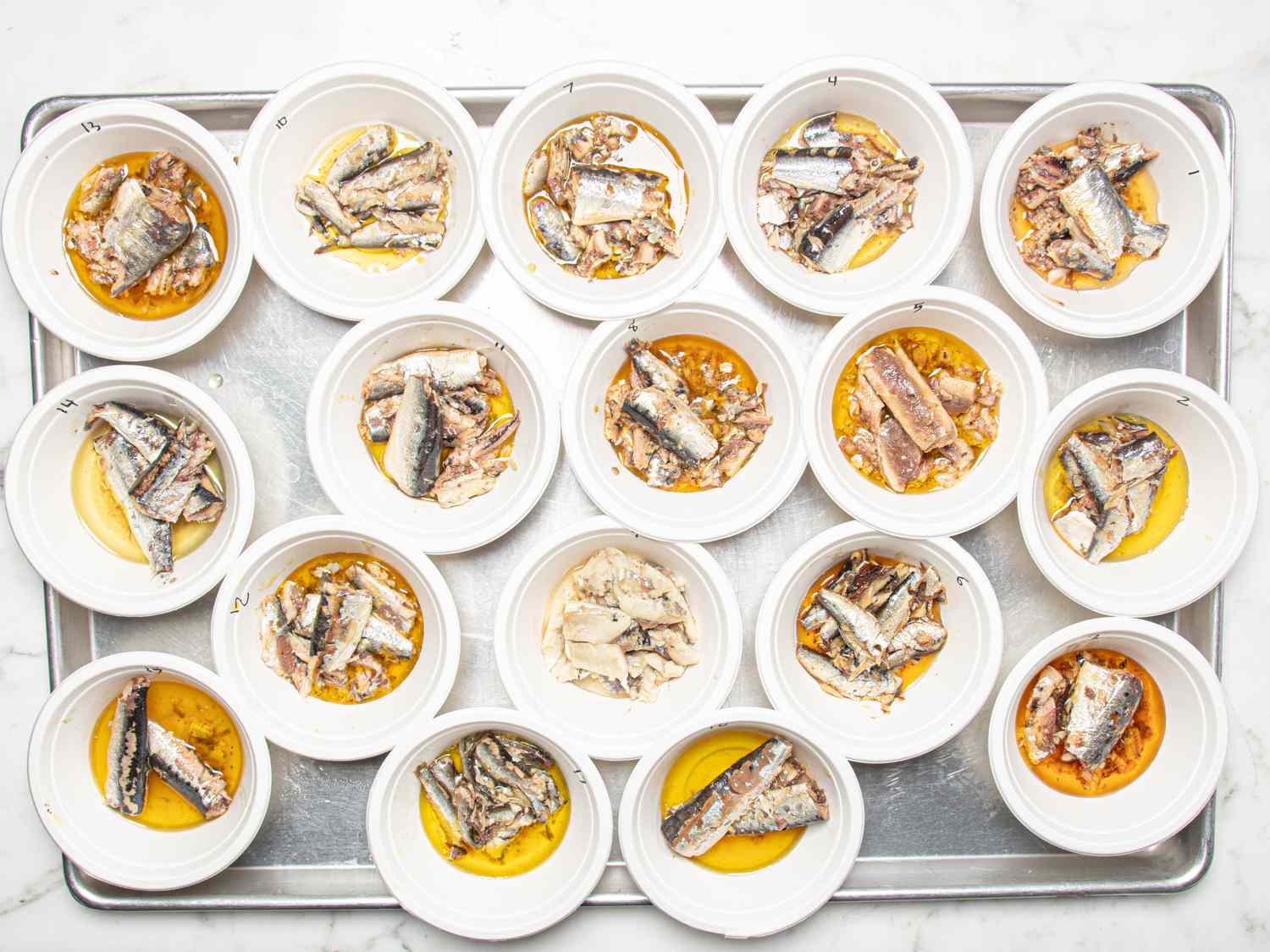 Multiple small bowls with sardines displayed on a tray