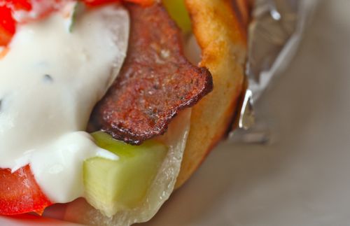Very close up image of corner of gyro sandwich, with crisp meat pertruding.