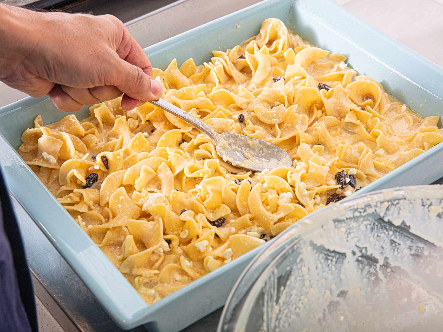 Overhead of putting noodle in baking dish 
