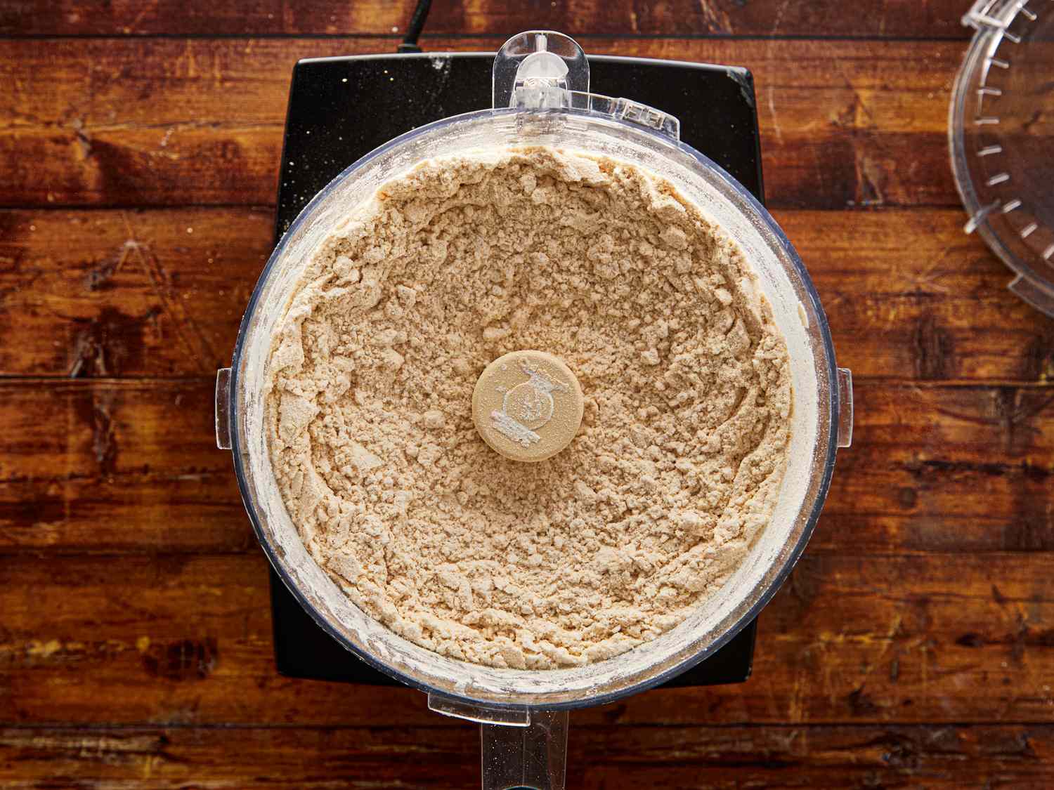 Food processor with flour or blended mixture on a wooden surface