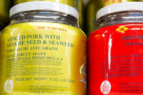 Two containers holding pork floss with sesame seed and seaweed.