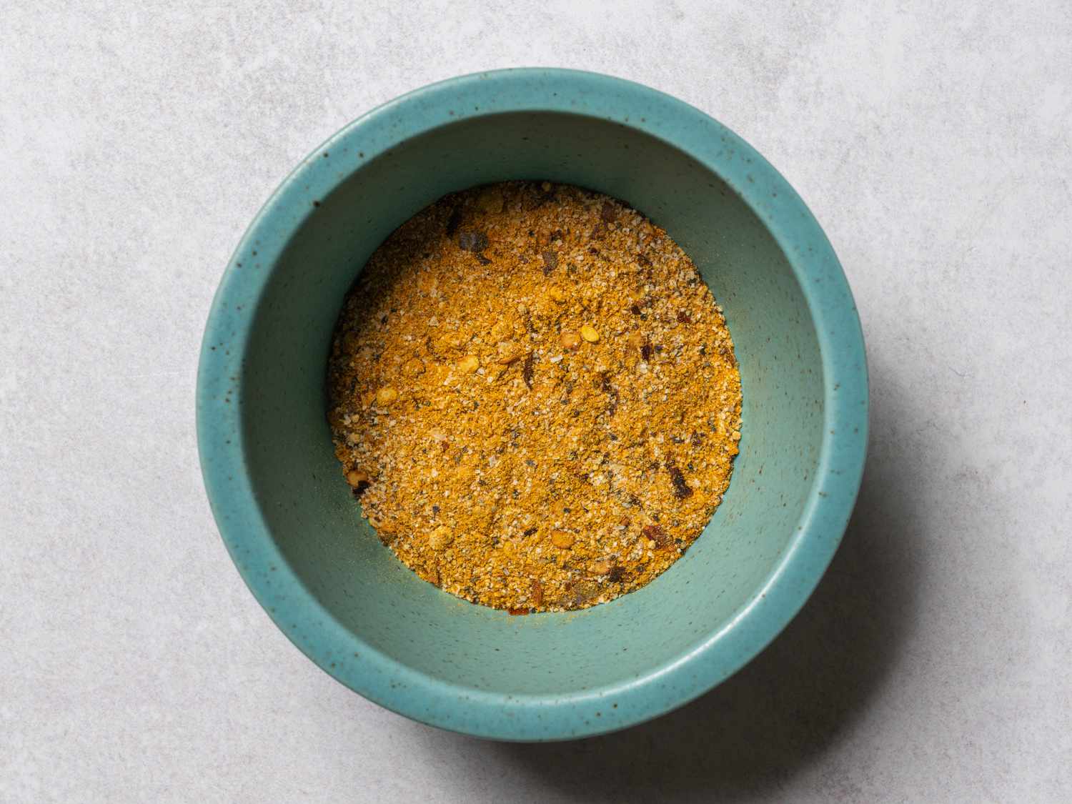 A small blue ceramic bowl holding the spice mix which will be spread on the cauliflower.