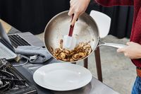 Person pouring mushrooms onto a plate from the Tramontina 12-Inch Stainless Steel Skillet