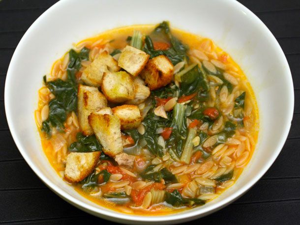 Overhead view of Swiss chard and pasta soup in a deep white bowl.