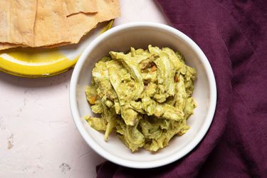 A bowl of pesto chicken salad with crackers on the side
