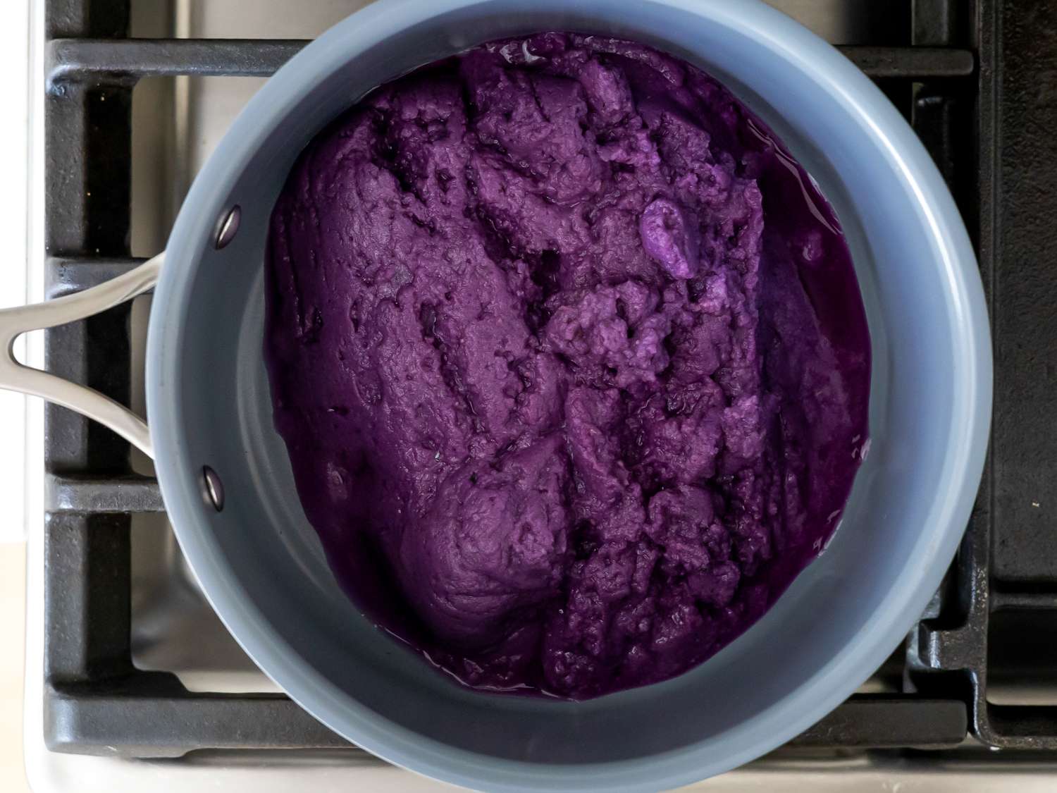 Overhead view of heating shredded ube in a saucepan.