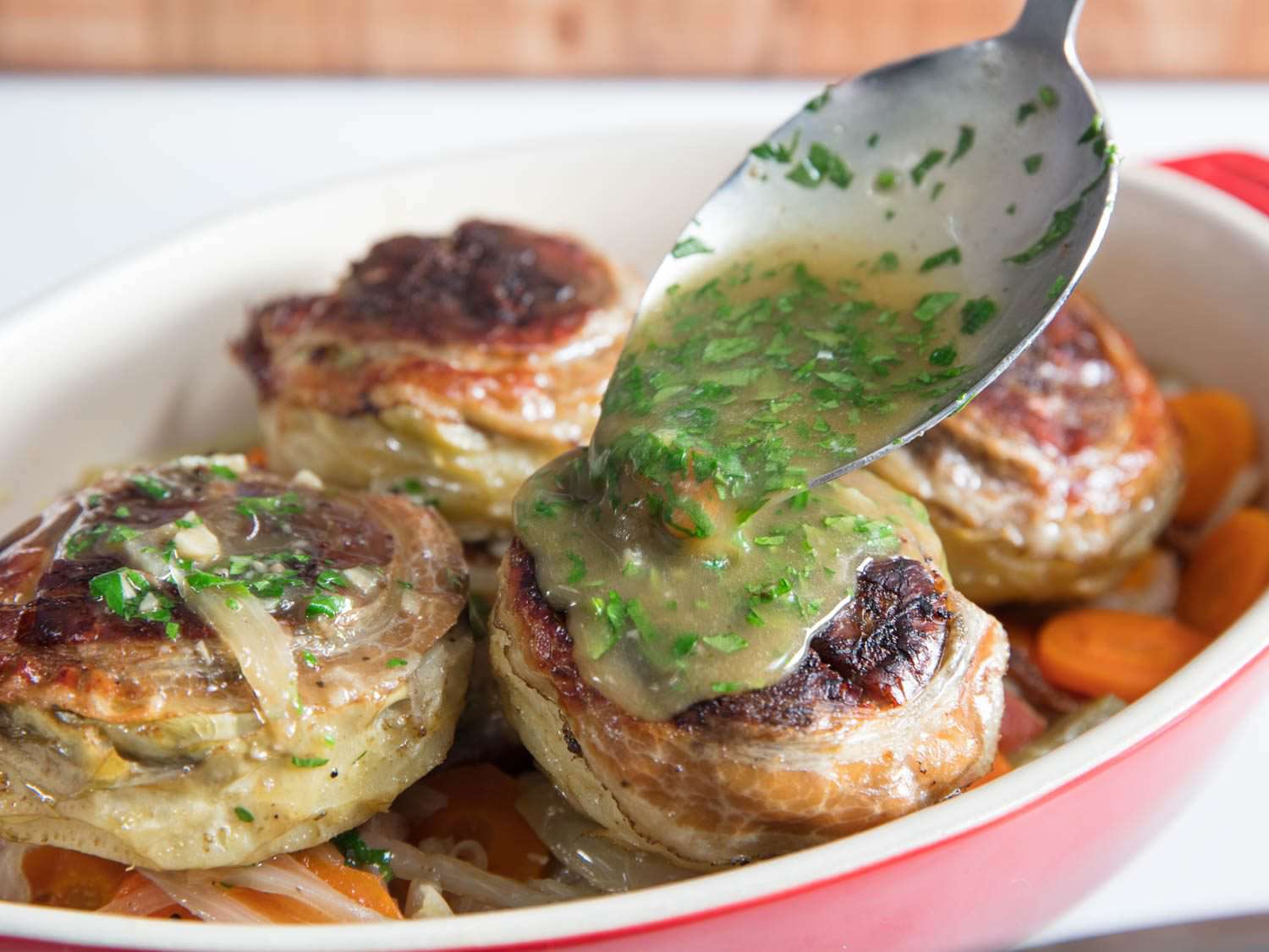 The reduced, enriched braisng liquid is spooned over the artichokes.