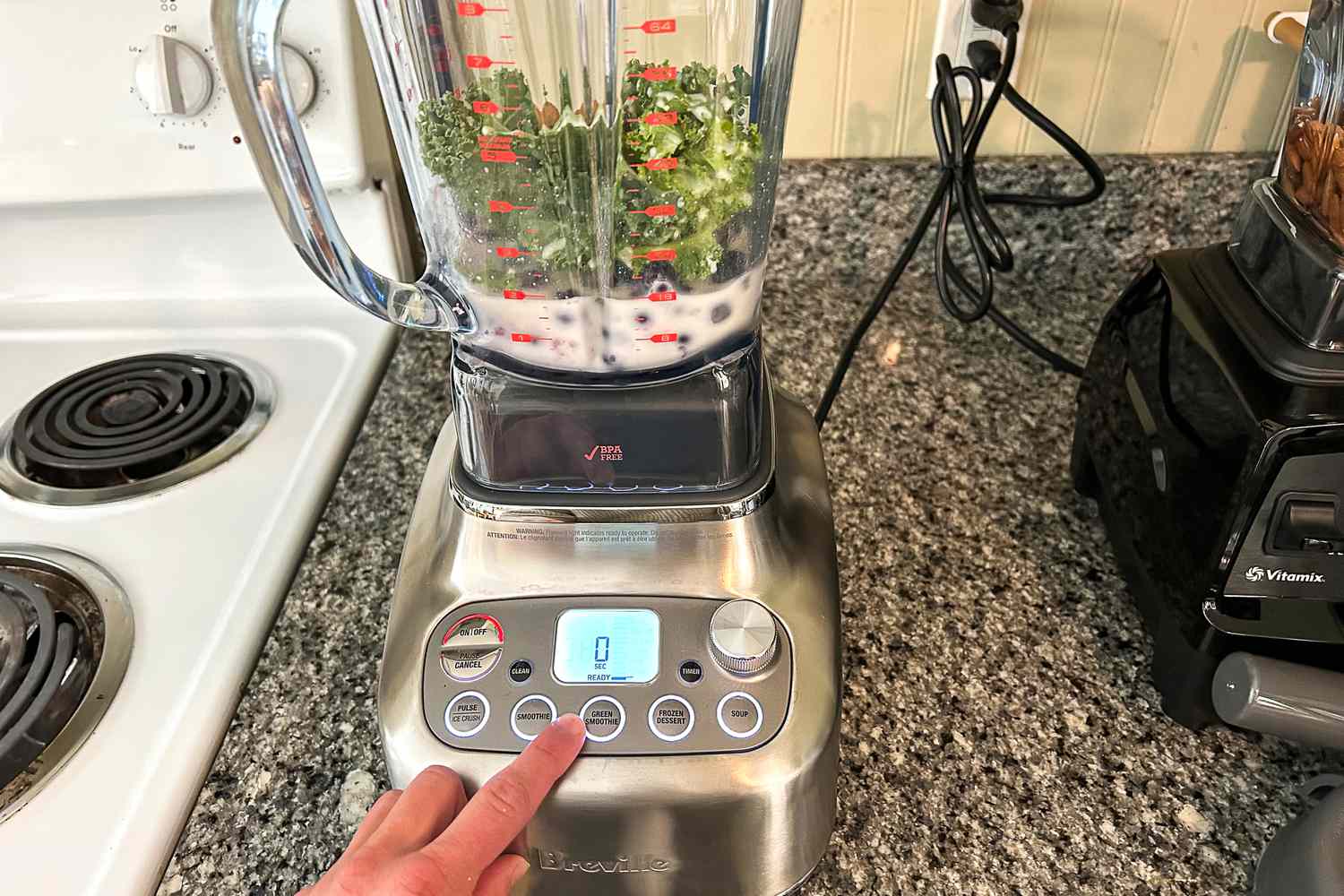 A hand pressing the preset buttons on the Breville Super Q blender.