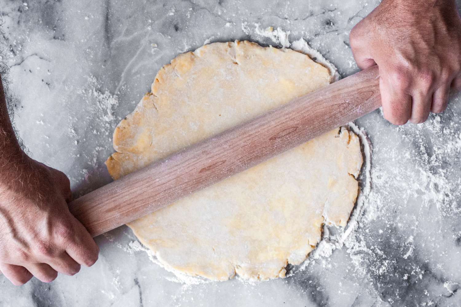 Person using a J.K. Adams Maple French Rolling Pin to flatten dough on a surface