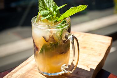 A plumpkin cocktail, served in a glass beer mug, garnished with a sprig of mint.