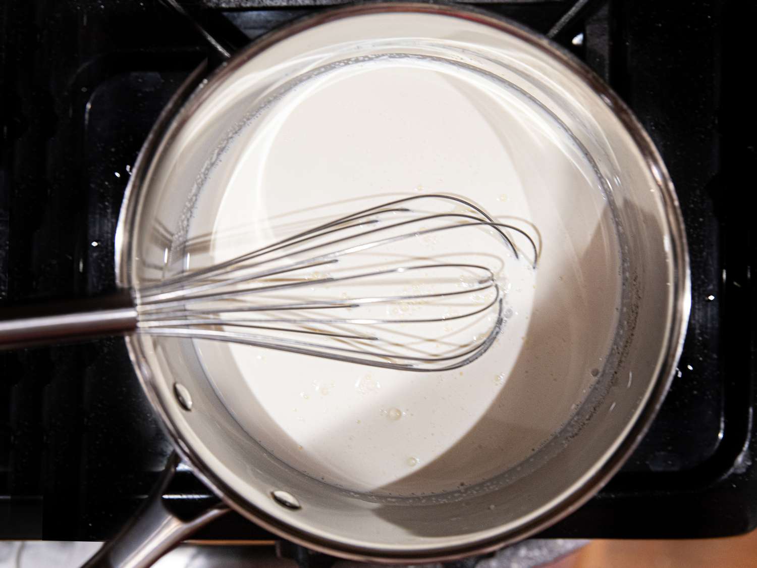 Overhead view of whisking sugar and heavy cream on a stove.