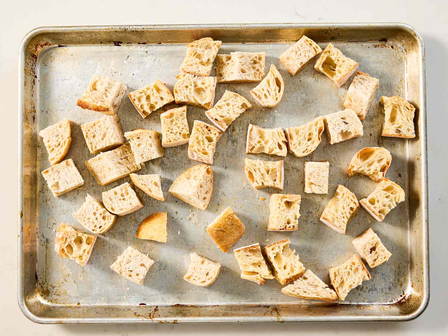 Cubed bread pieces spread on a baking sheet