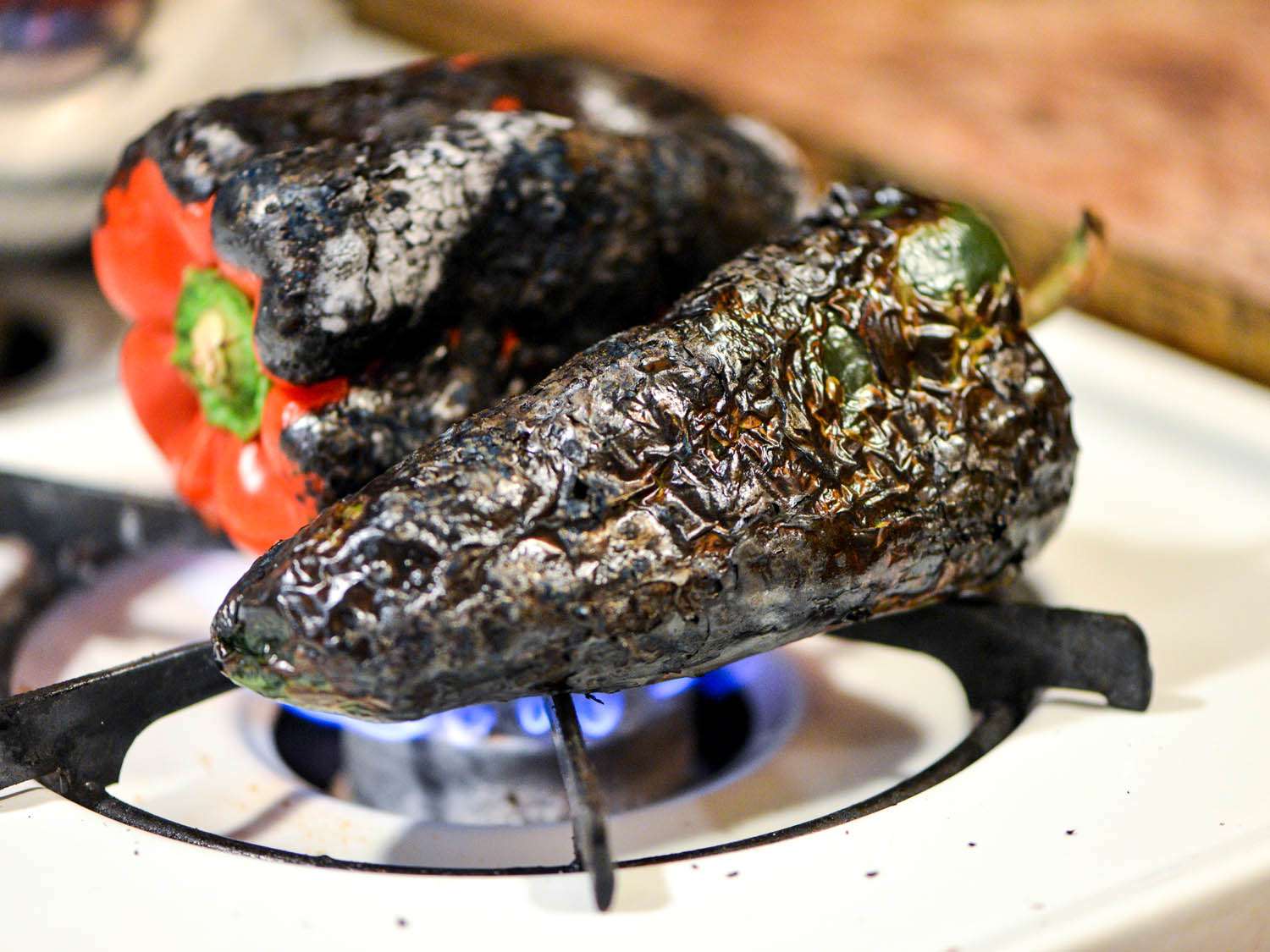 Blackening peppers over stovetop flame.
