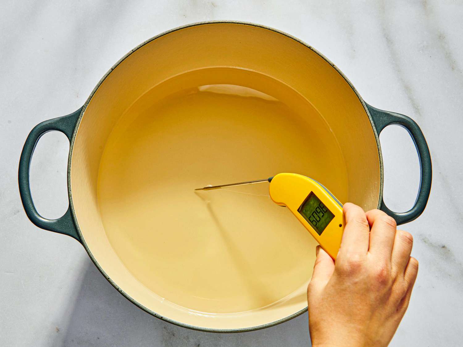 Dutch oven with heated oil and thermometer reading temperature 