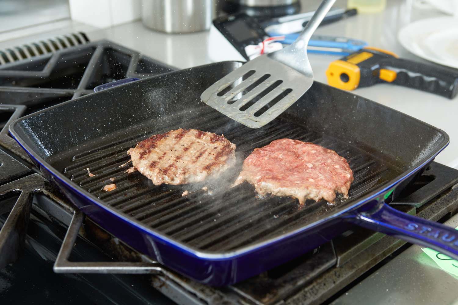 Two burgers being grilled using the Staub Enameled Cast Iron Grill Pan