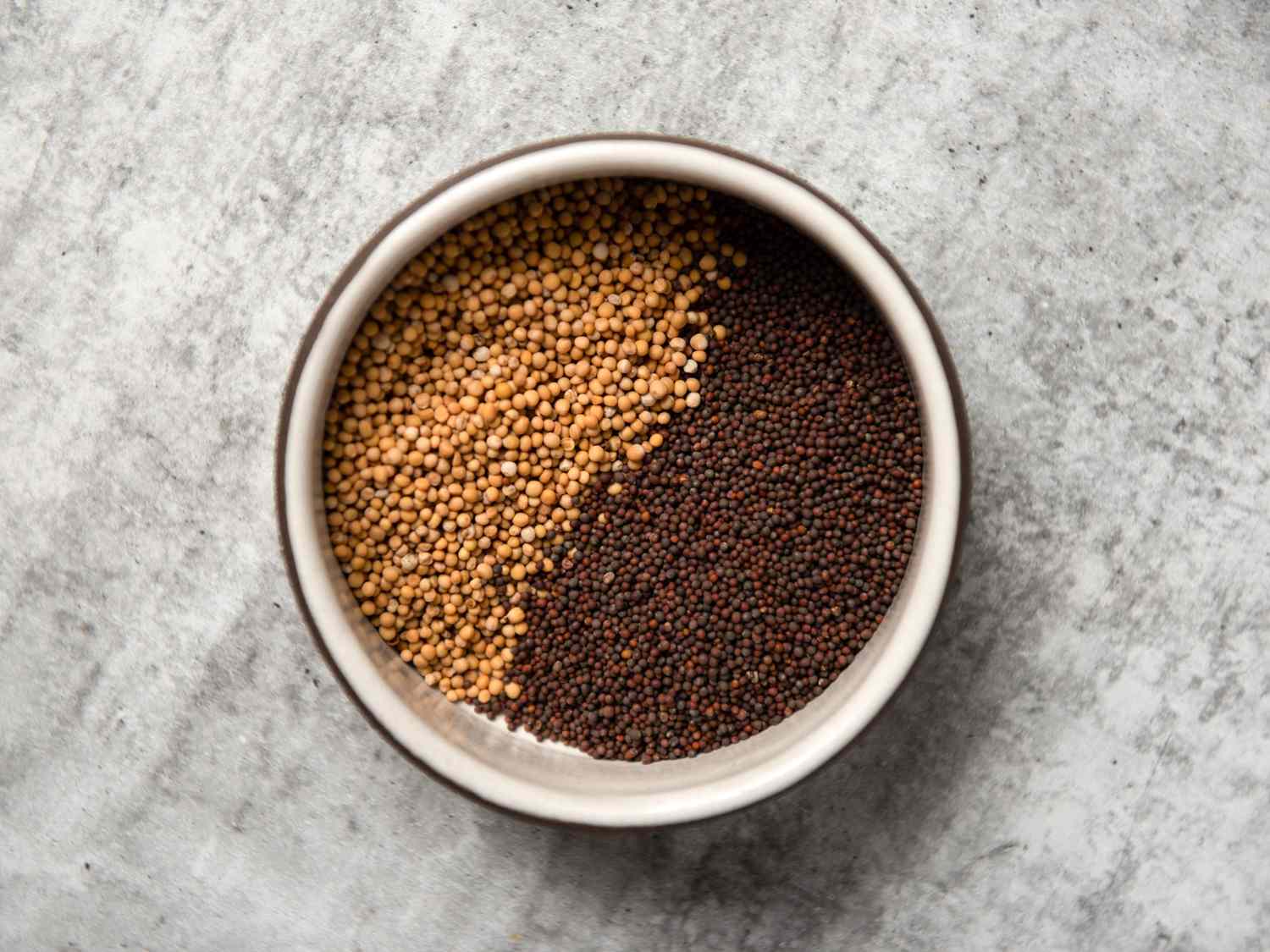 white and black mustard seeds in a bowl