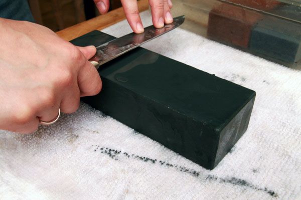 Hands sharpening a knife on a lower grit whetstone