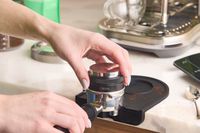A person using the Crema tamper to tamp espresso grounds.