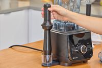 A hand grabbing an accessory from the Vitamix Ascent X2
