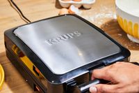 Person holding handle on Krups 4-Slice Belgian Waffle Maker