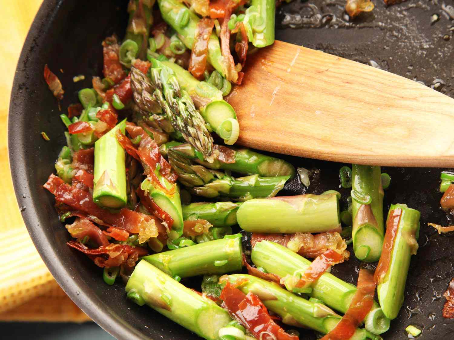 Sautéing prosciutto and asparagus in a pan for a homemade gnocchi dish. 