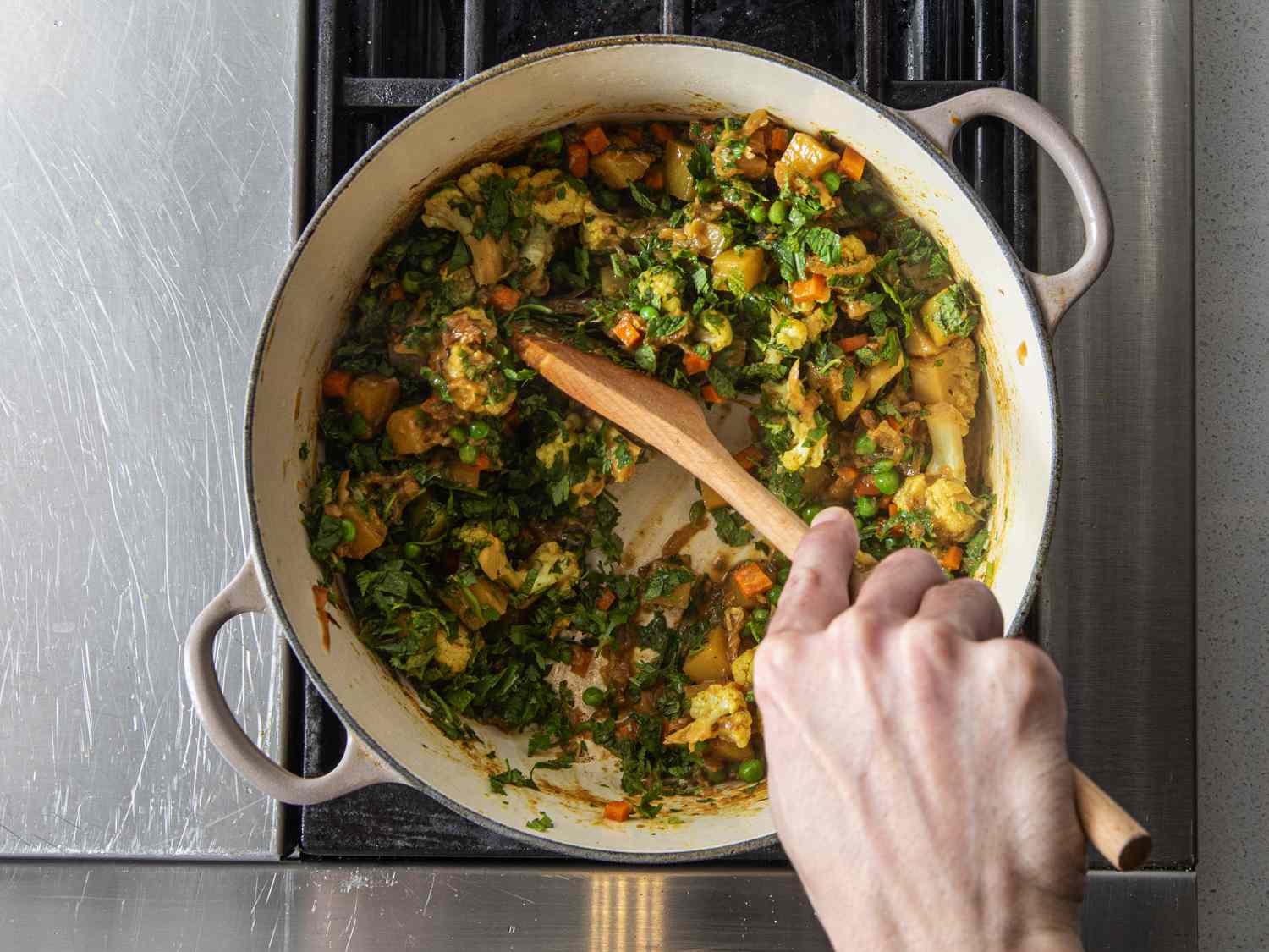Mint and cilantro being added to dutch oven 