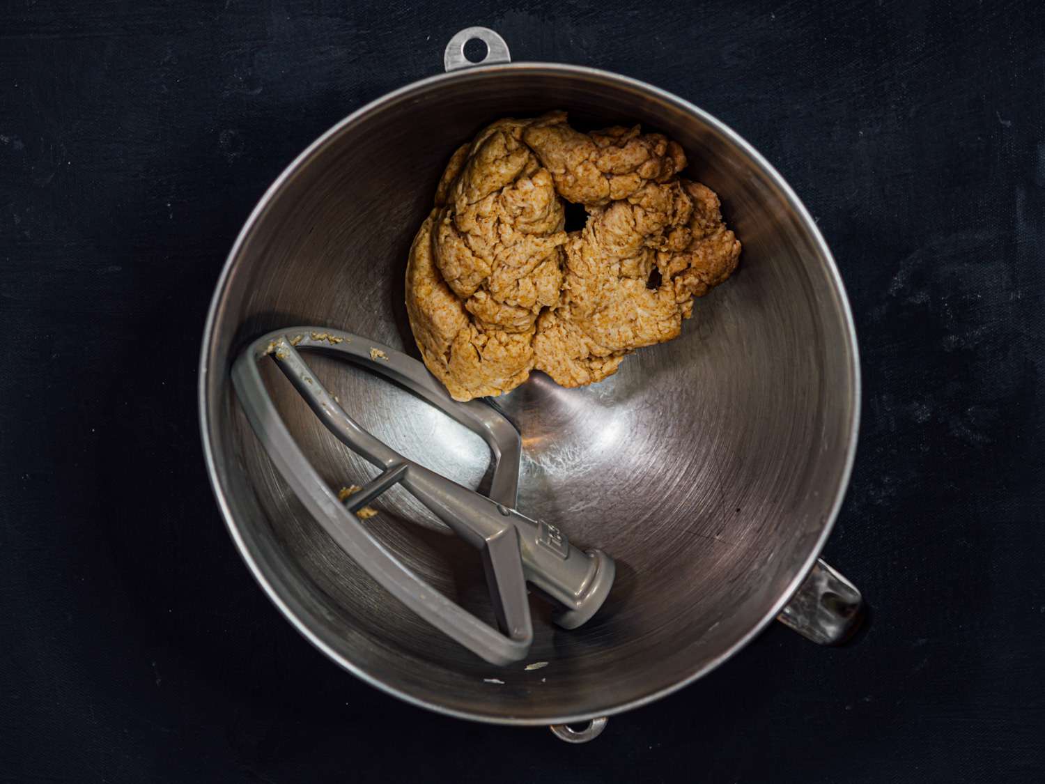 The mixed dough in the bowl of a stand mixer.