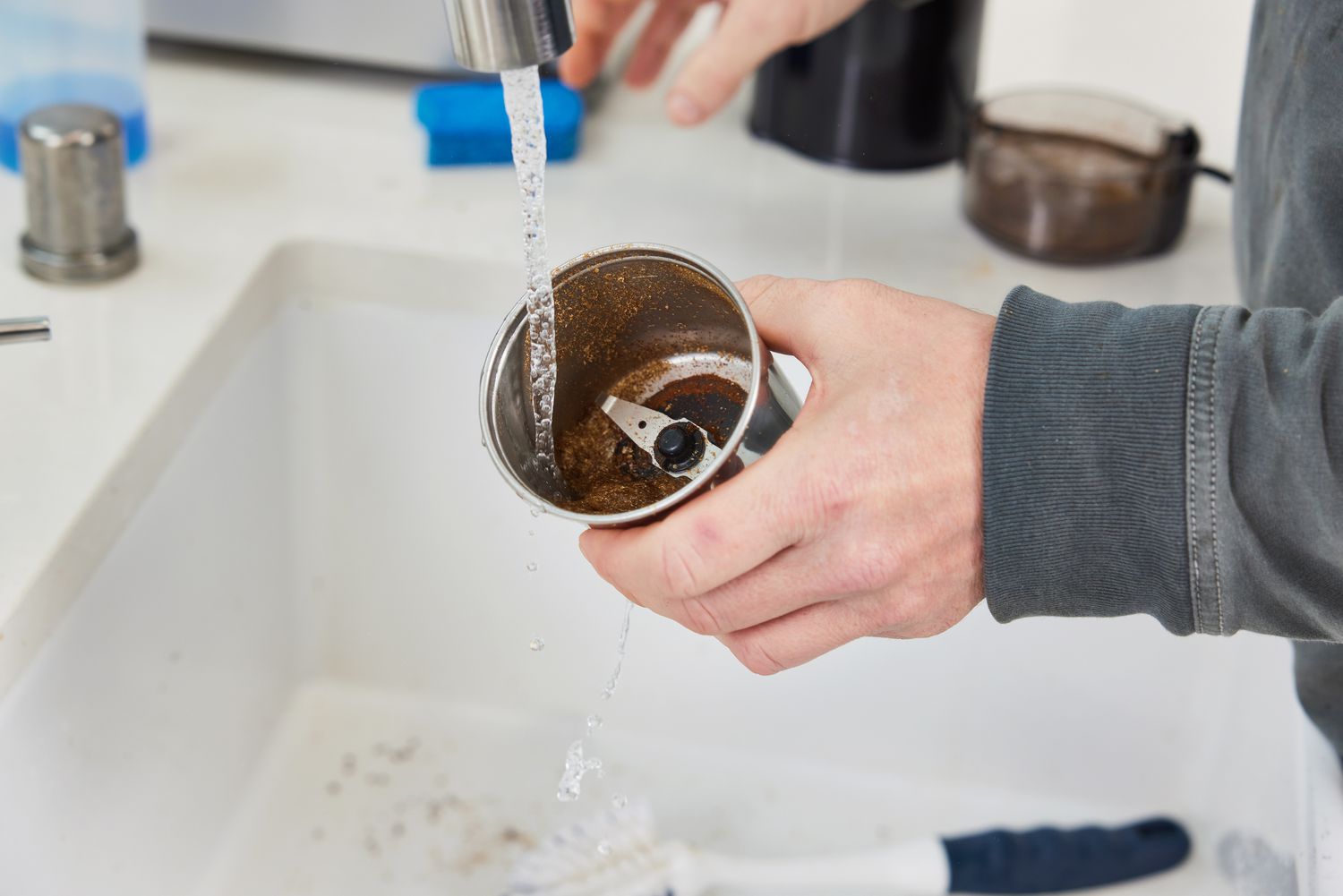 A person washing the cup of a blade grinder