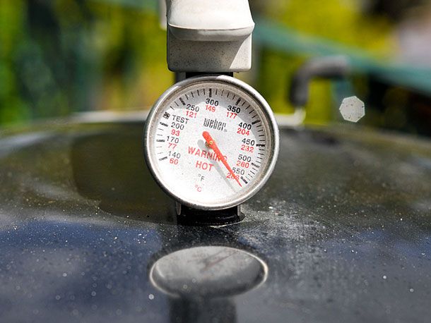 A thermometer on top of a grill. 