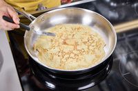 A person makes a crepe in the Tramontina 12-Inch Stainless Steel Skillet